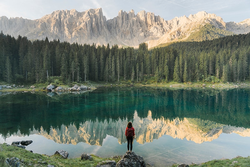 woman looking over body of water in the mountains